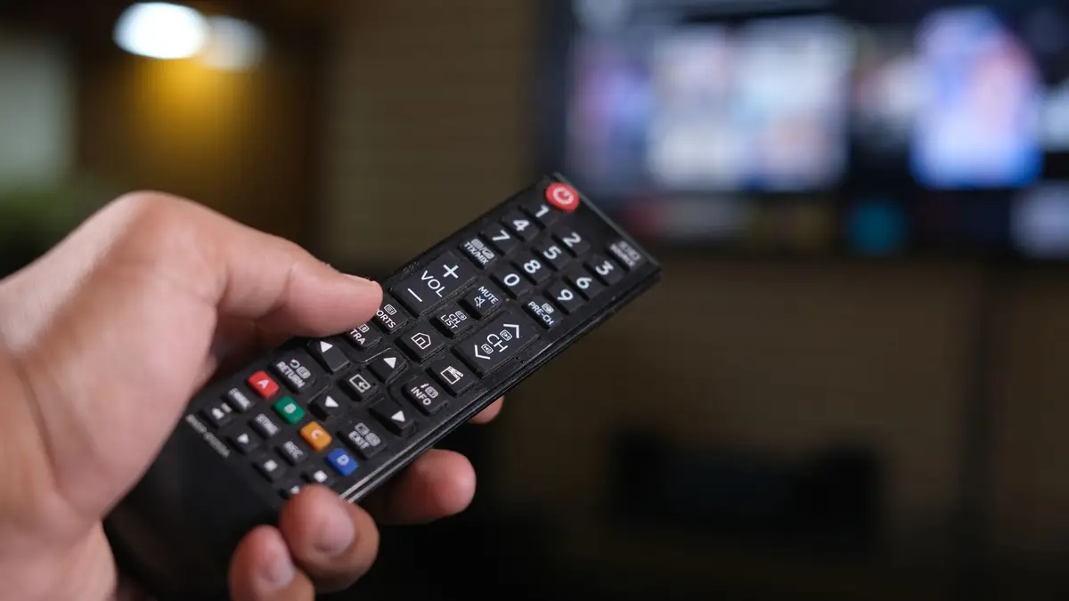Television remote held in front of a streaming screen