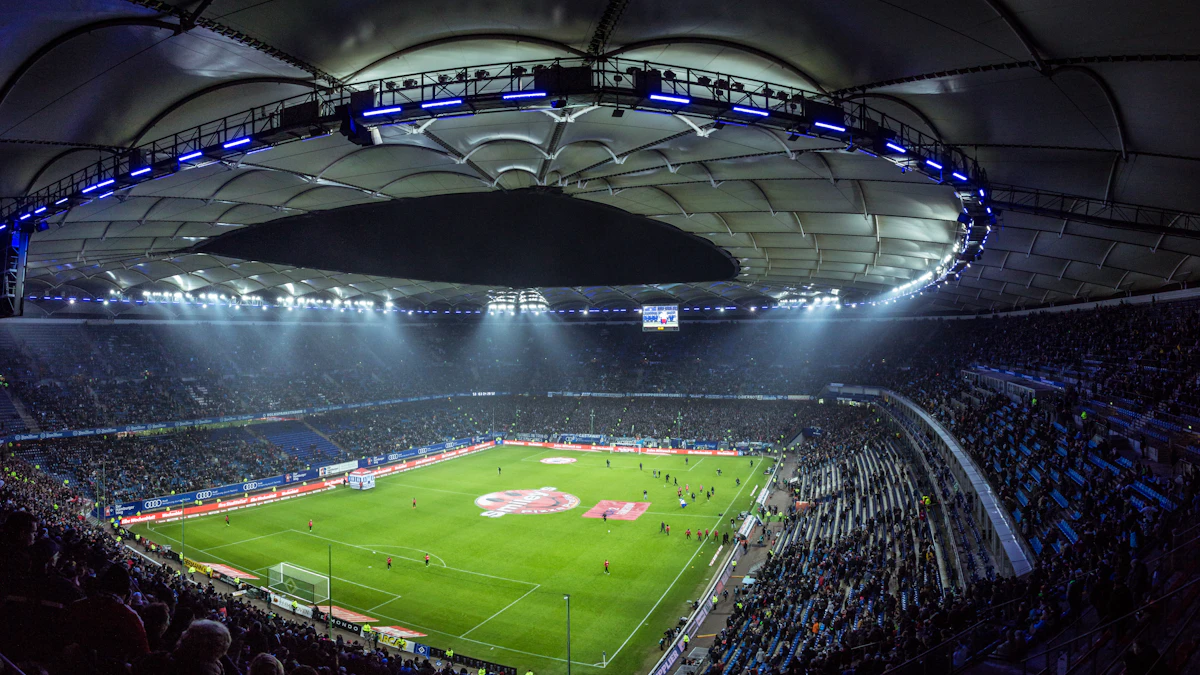 Live football match on a floodlit pitch beneath a covered stadium roof