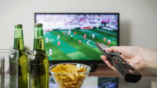 Football match playing on a television with snacks ready