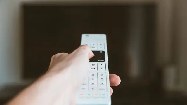 Hand changing television channels with a remote control
